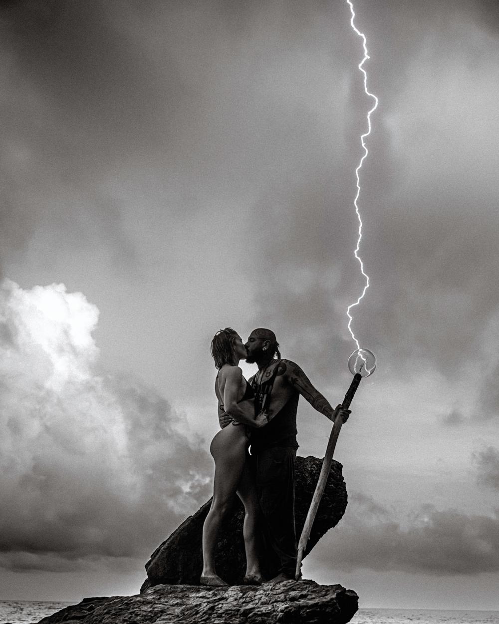 Ohrangutang and Alanna Jade on a rock by the sea under a lightning storm